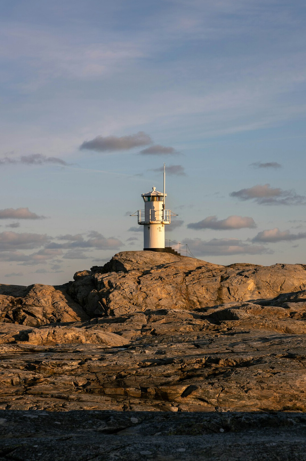White lighthouse on a rocky coast at dusk